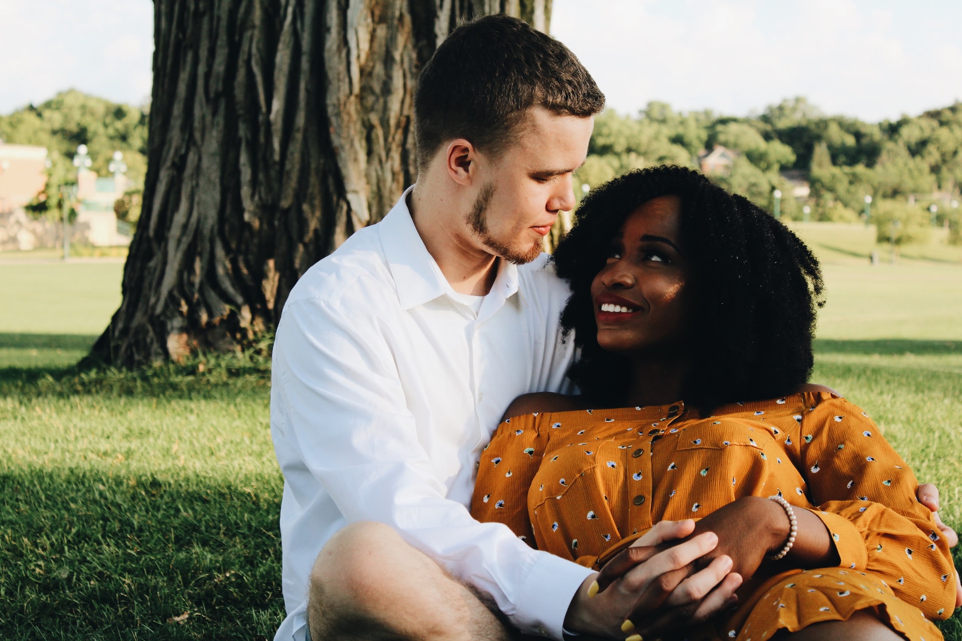 Image of a man and woman lying together in a park and smiling at one another. After meeting with a culturally sensitive therapist for culturally sensitive therapy in Los Angeles, CA, couples can feel like they're on the same page. | 90404 | 90503