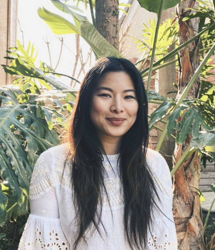 Image of a woman surrounded by greenery looking at the camera and grinning. If you are experiencing anxiety, working with an Asian therapist in Los Angeles, CA can help you ground yourself. | 91108 | 90232