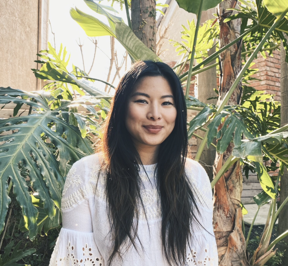 Image of a woman surrounded by greenery looking at the camera and grinning. If you are experiencing anxiety, working with an Asian therapist in Los Angeles, CA can help you ground yourself. | 91108 | 90232