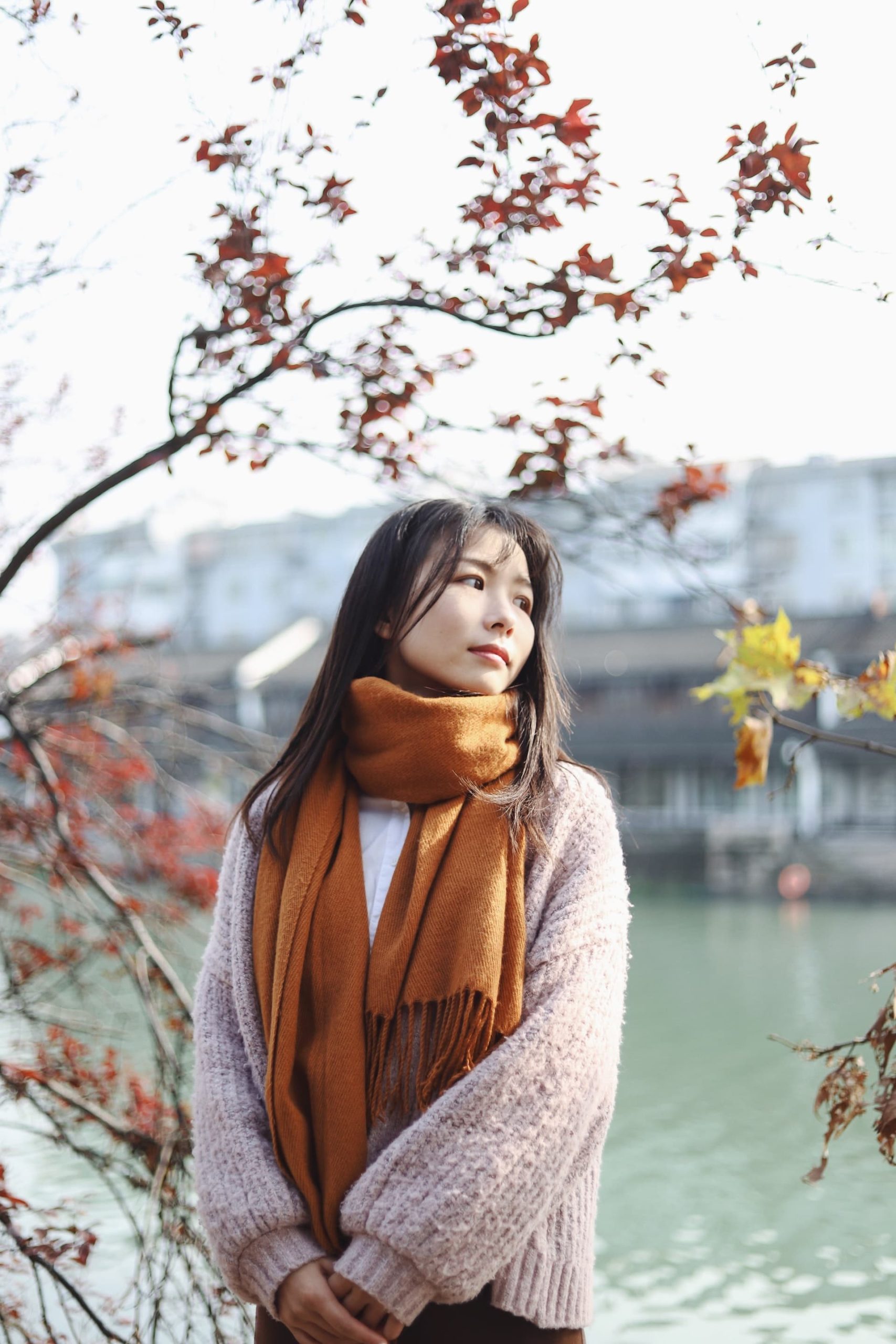 Image of a young woman standing next to a river wearing an orange scarf. She represents an adolescent who may seek support from a teen therapist in Los Angeles, CA. Therapy for teens in Los Angeles, CA can help teenagers and young adults explore themselves. | 91006 | 90071 |