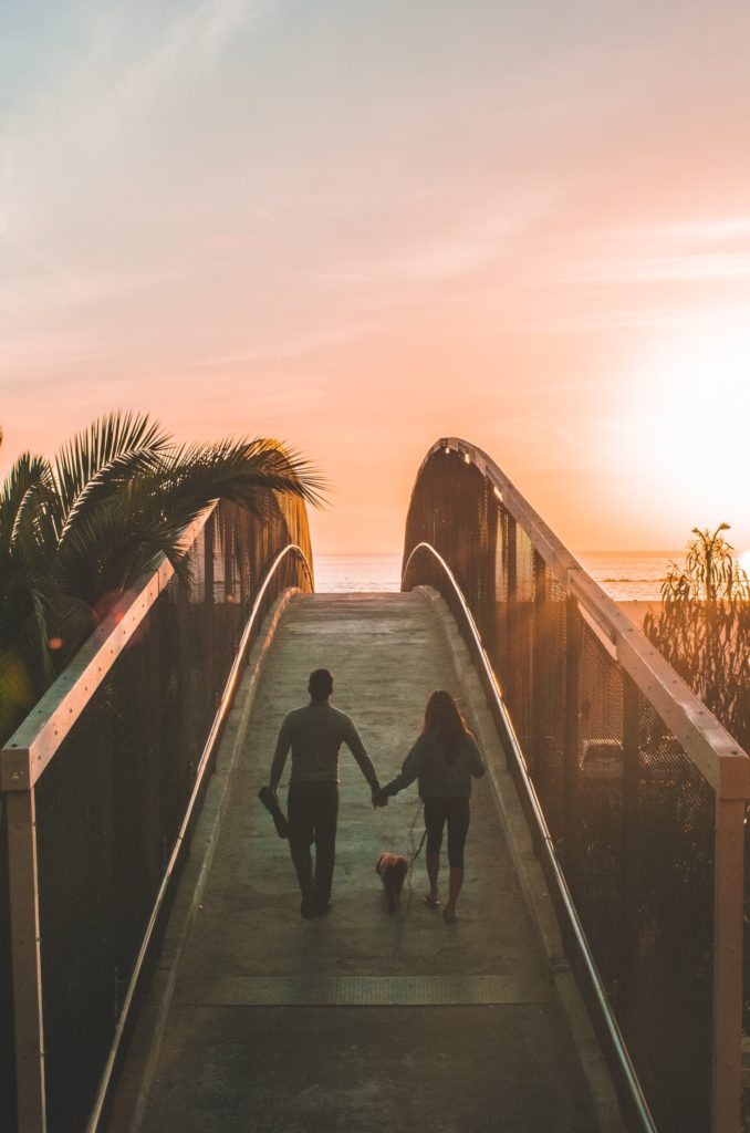 Image of a couple walking across a bridge and toward a sunset. Working with a marriage counselor in Los Angeles, CA can help you strengthen your relationship during couples therapy in Los Angeles, CA. 91006 | 90071