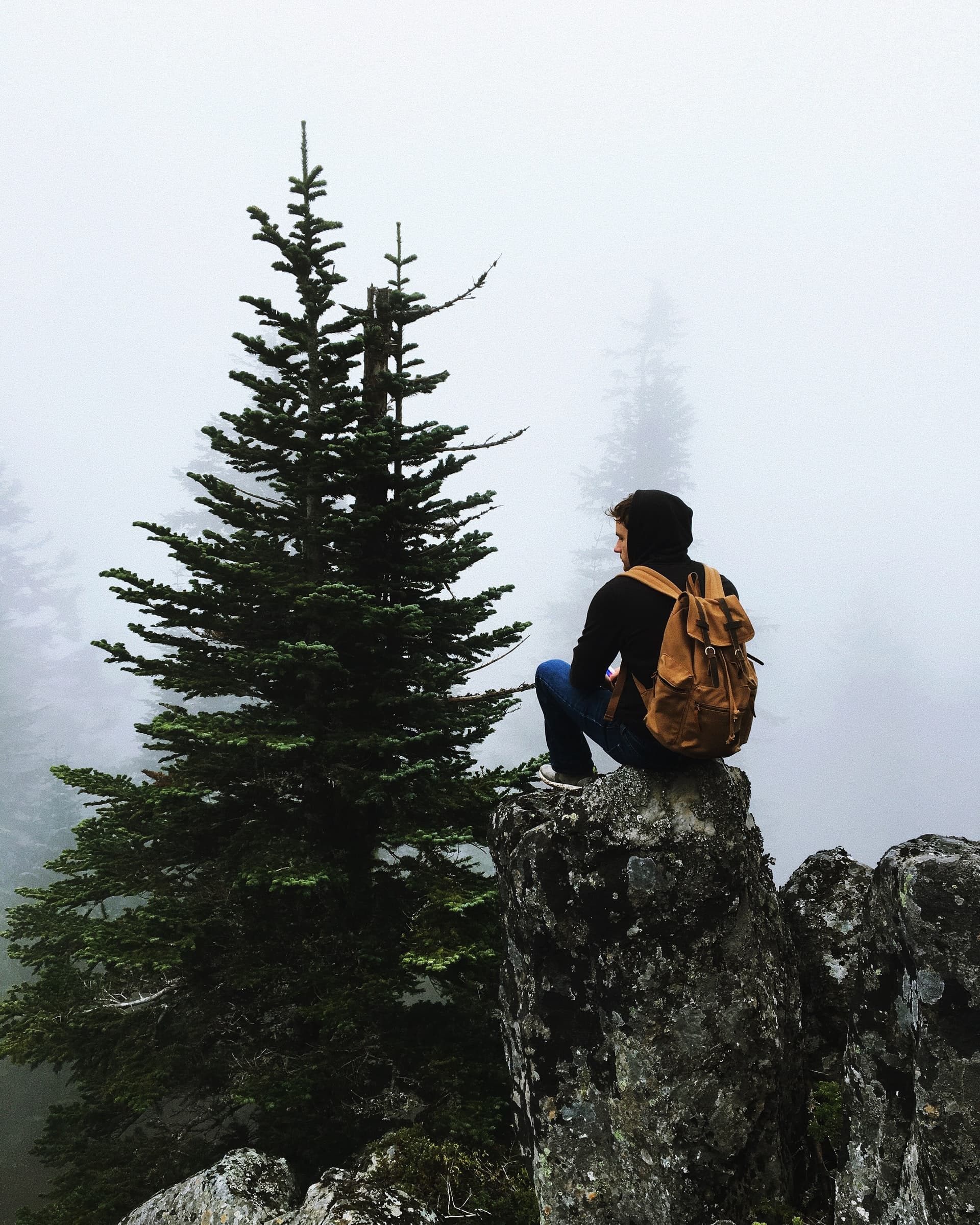 Photo of a young man hiking and sitting on a rocky ledge relaxing. This photo illustrates the isolation one can experience from anxiety. It can help to look for anxiety treatment in Los Angeles, CA. 90404 | 90503
