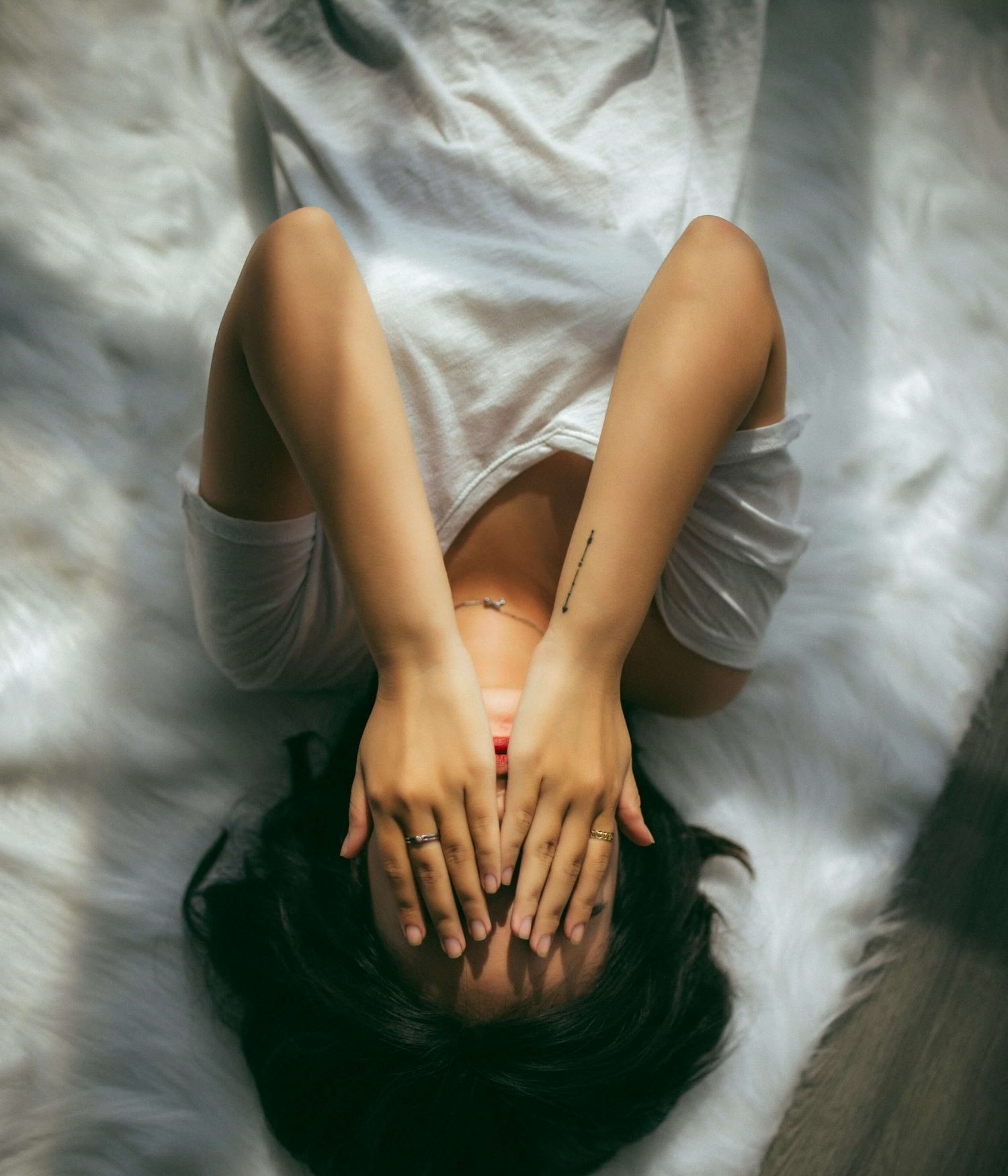 Image of a woman lying on the floor with her hands held over her face. This image illustrates the exhaustion many people experience before postpartum therapy in Los Angeles, CA. You can get support from a postpartum therapist in Los Angeles, CA. 91108 | 90232