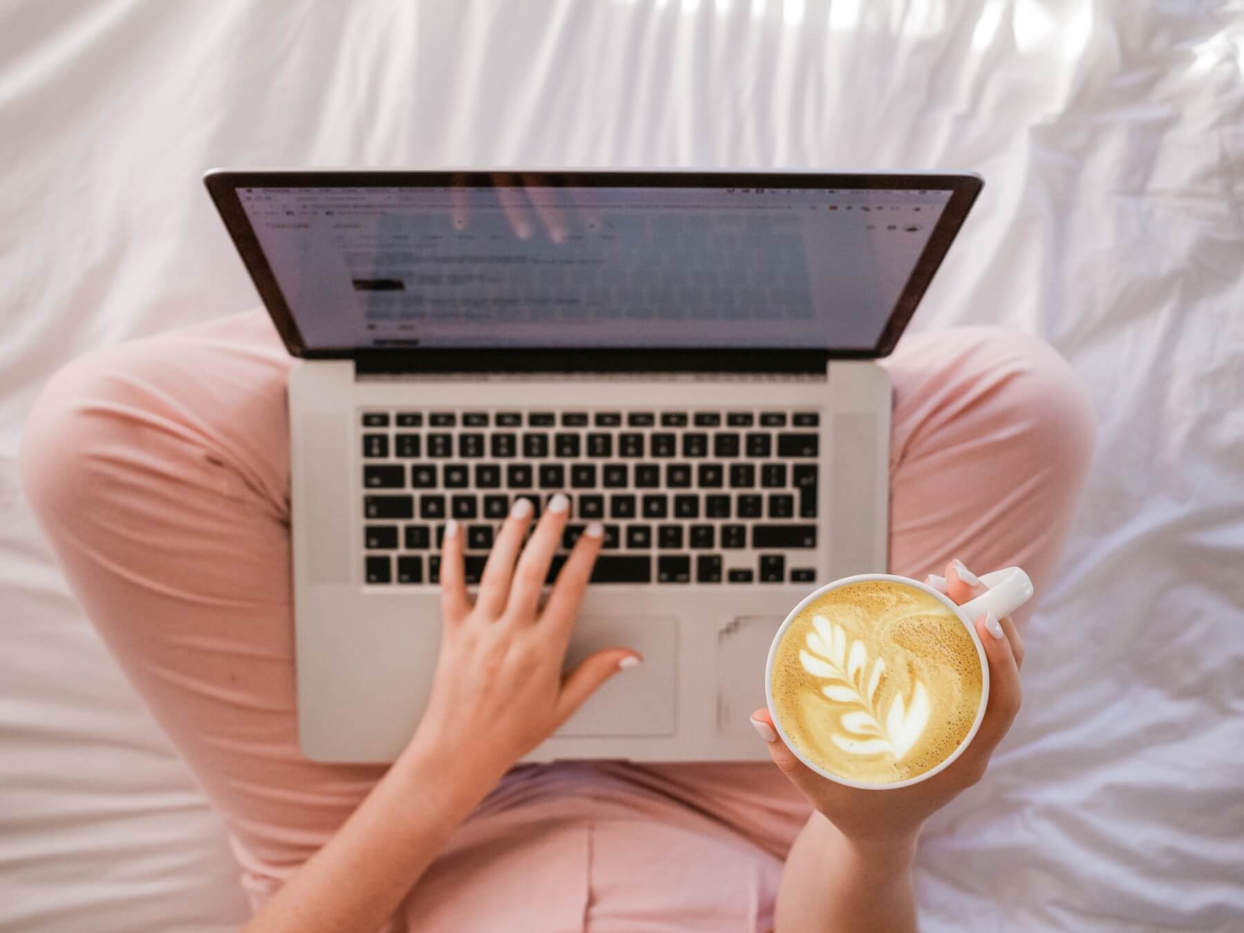 Image from an aerial view of a woman sitting in bed with her laptop and coffee. This image illustrates the convenience of using online therapy in California to meet with an online therapist in Los Angeles, CA. Couples can use online couples therapy in California to work with both of their schedules. | 90504 | 90505