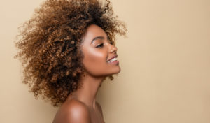 Image of the side profile of a Black woman smiling. This image depicts how one can find freedom from effects of racial trauma after working through trauma therapy in Los Angeles, CA. 90404 | 90503
