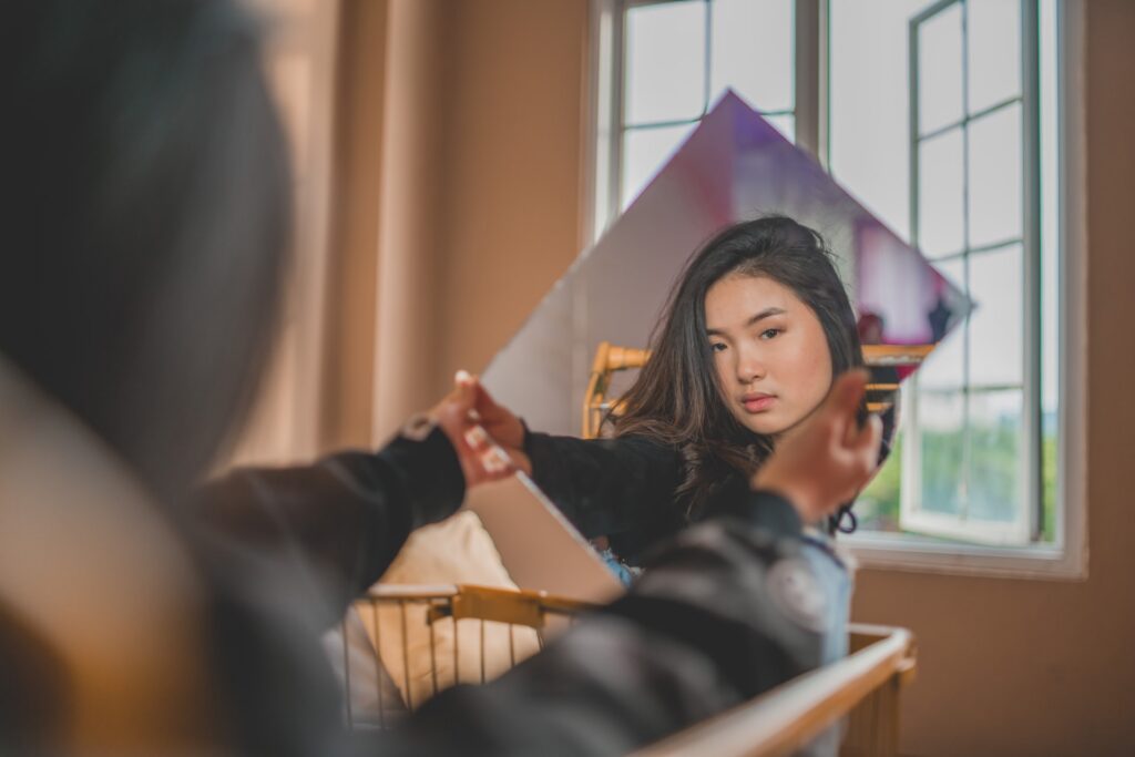 Asian woman looking at her reflection in mirror. (90404, 90503, 91006.) We have therapy for asian women in Los Angeles, CA if you’re struggling with the asian american experience. Asian american therapist in Los Angeles, CA can help you.