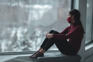 asian woman sits in a window. This represents the toll the american body image can take on Asian women. Get support from an asian therapist at Yellow Chair Collective who offers therapy in Los Angeles, CA 