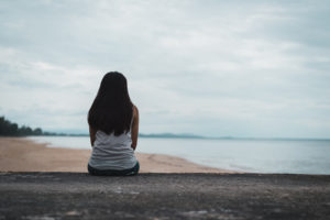 Image of person sitting near the beach. This person could be thinking about how to include work stress management in her life. She could perhaps benefit from burnout treatment with a burnout therapist in Los Angeles, CA. (90404, 90503, 91006).