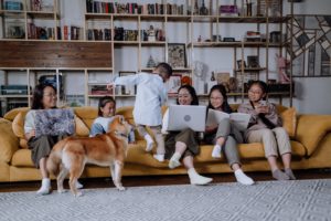Family sitting on a couch with their laptops. This image depicts a family who could benefit from culturally sensitive therapy in Los Angeles, CA. Check out our Asian American therapists today. | 90404 | 90503