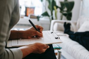 Image of a person writing notes using a clipboard. This image represents someone filling out intake paperwork before starting virtual EMDR sessions. Get connected with an EMDR therapist in Los Angeles, CA for PTSD treatment today. | 90404 | 90503