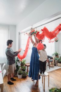 Photo of an Asian woman, man, and child setting up decorations for Lunar New Year. This image represents an Asian family who could benefit from working with an Asian therapist in Los Angeles, CA. 90404 | 90503