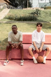 Content young diverse Asian teenage guys relaxing on bench after basketball training representing the fulfillment they can experience from working with a Los Angeles, CA-based Asian American teen therapist. To find an Asian American therapist in Los Angeles, reach out!
