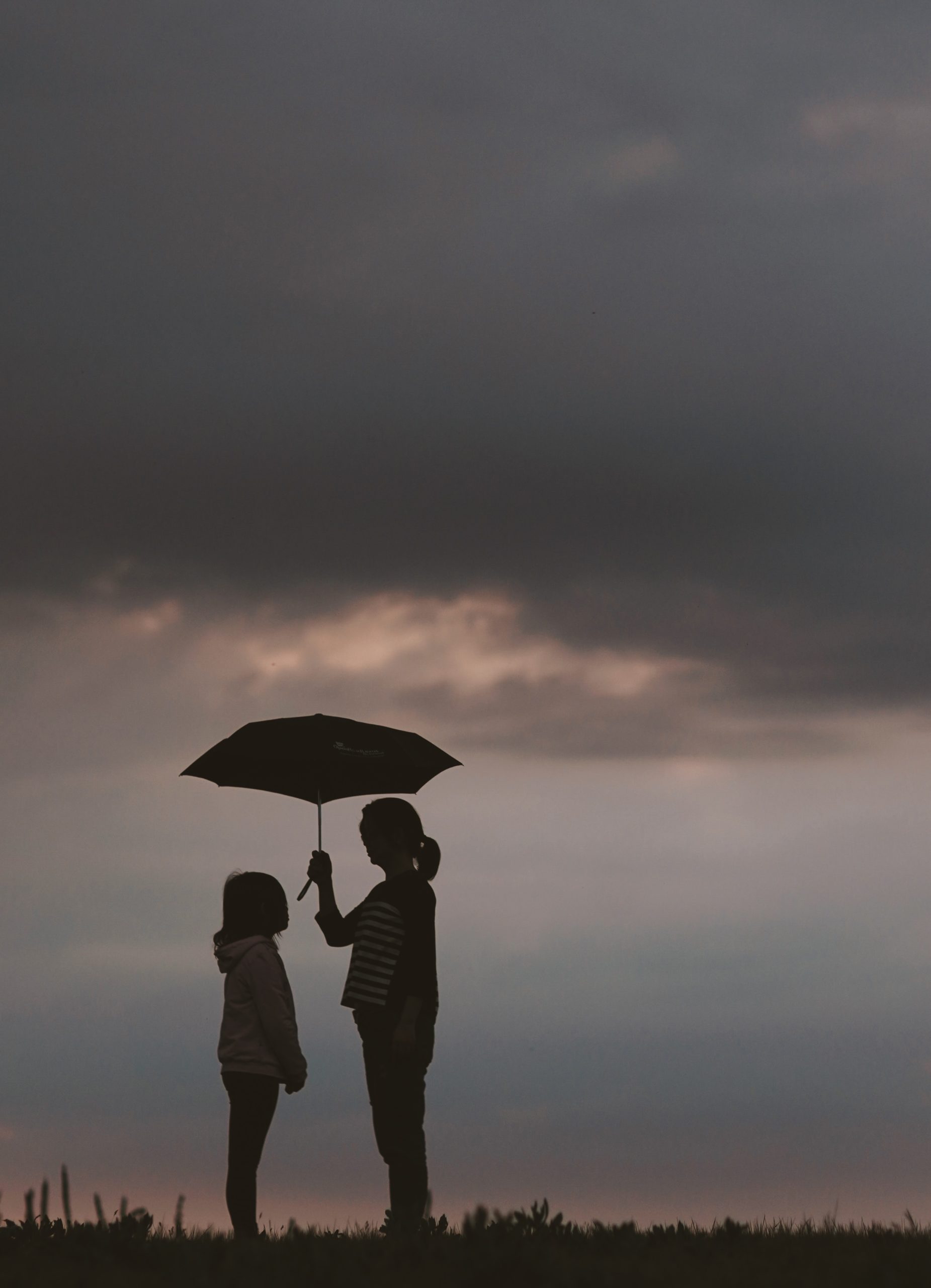 Person holding umbrella for another person. An Asian American therapist in Los Angeles or New York can help with Asian American Therapy near you.