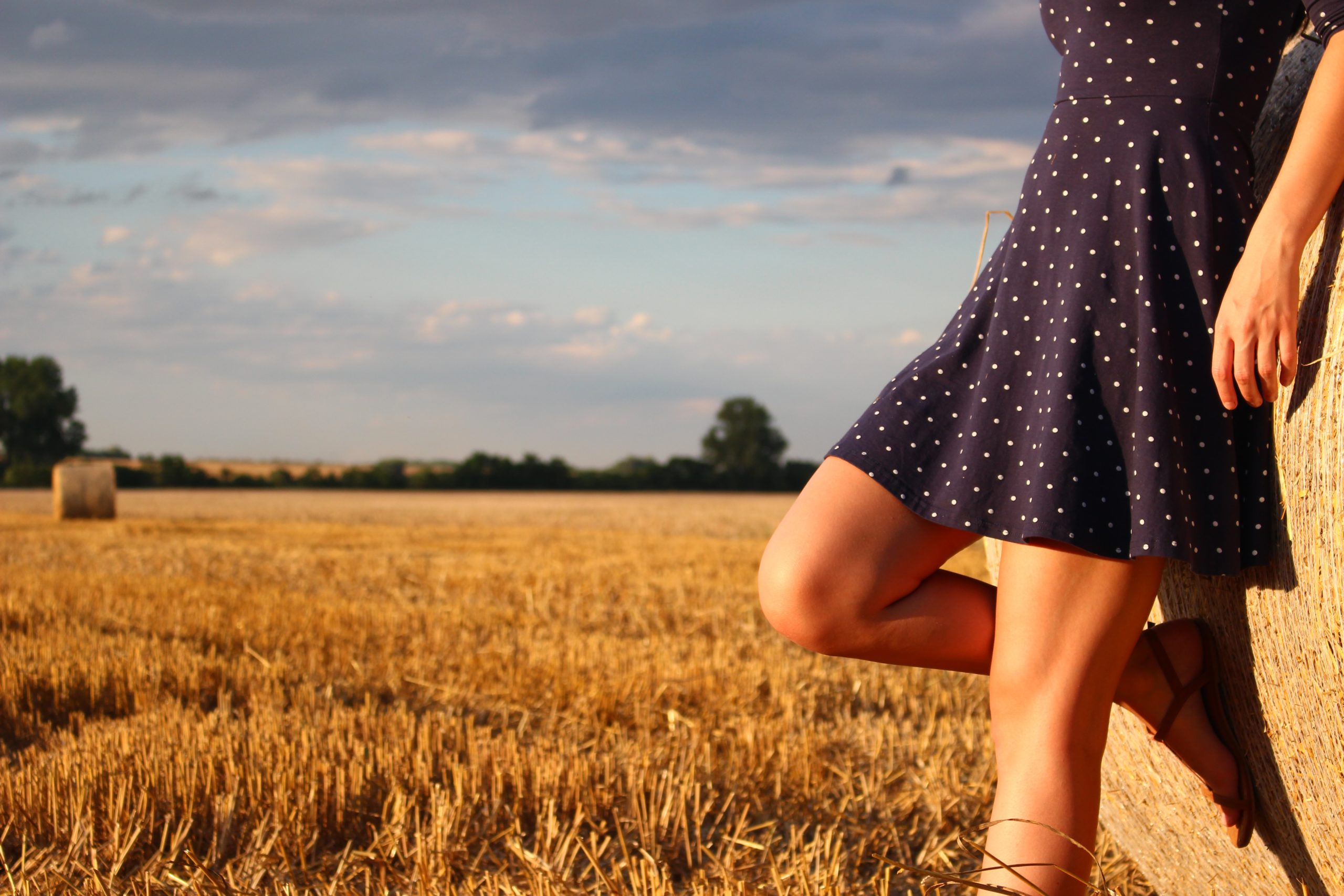 Person in a sundress leaning on a bale of hay in a field. Feel supported by a Los Angeles based group therapy practice that specializes in Asian American mental health. An Asian American therapist in Los Angeles or New York can help with Asian American Therapy near you.