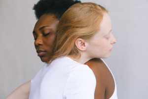A multiracial, gay couple embracing one another representing connection despite their differences because they received therapy on how to empower one another in their differences.