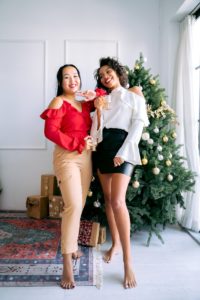 Two friends pose for a holiday photo in front of a Christmas tree. Learn how a stress management therapist in Los Angeles, CA can offer support this season. Search for Asian American therapy or therapy for empaths to create healthy boundaries. 
