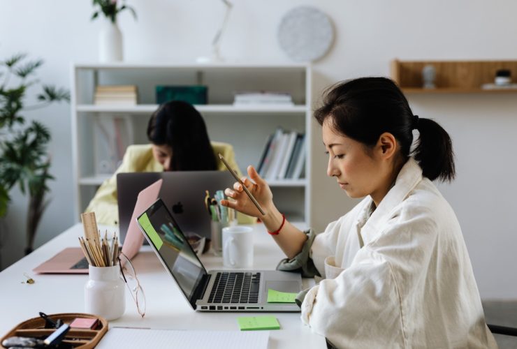 A woman focuses on her laptop while holding a pencil in her hand. This could represent overcoming the struggles of adult ADHD in Los Angeles, CA that an Asian American therapist can offer support with overcoming. Learn more about adult ADHD therapy in Los Angeles, CA, and other services.