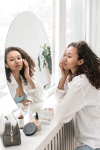 A woman looks at herself in the mirror representing the weight that Asian Americans carry when it comes to perceptions of others. An ADHD therapist in Los Angeles, CA can offer support with adult ADHD therapy and coaching in Los Angeles, CA to overcome expectations. 
