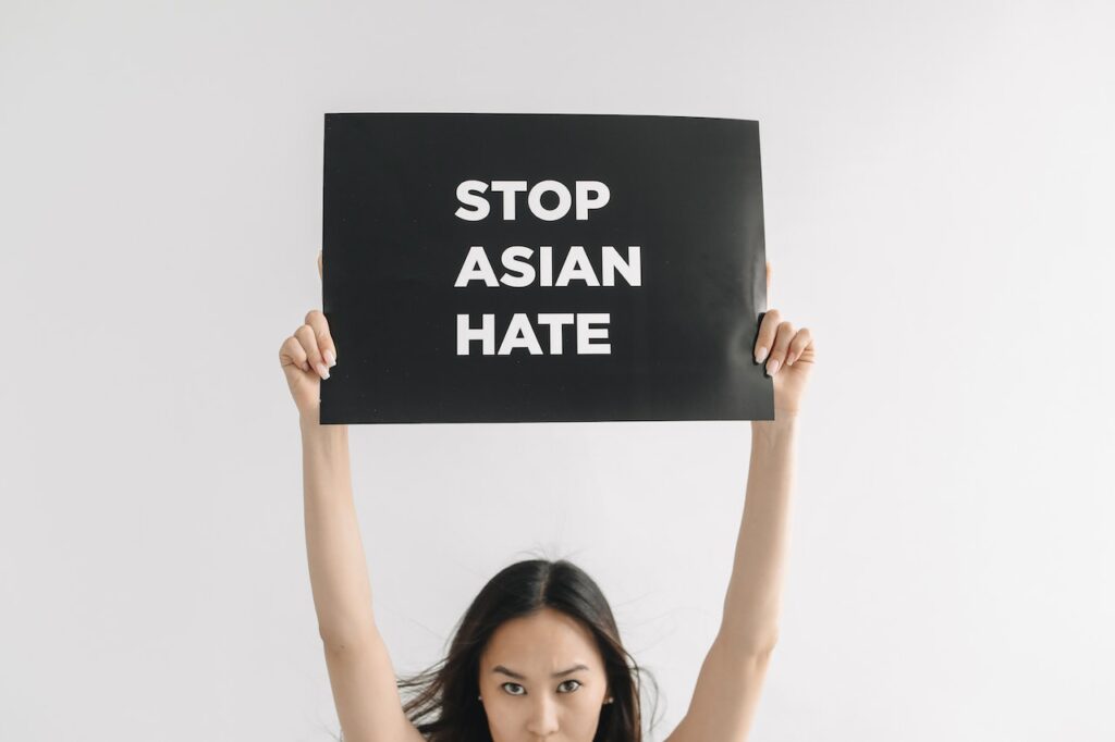 An Asian American woman holding a sign that states "Stop Asian Hate" to represent the racial trauma Asians and Asian Americans experienced that cause negative impacts on their mental health and how EMDR therapy can help the healing process.