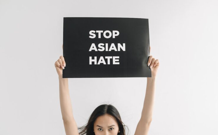 An Asian American woman holding a sign that states "Stop Asian Hate" to represent the racial trauma Asians and Asian Americans experienced that cause negative impacts on their mental health and how EMDR therapy can help the healing process.