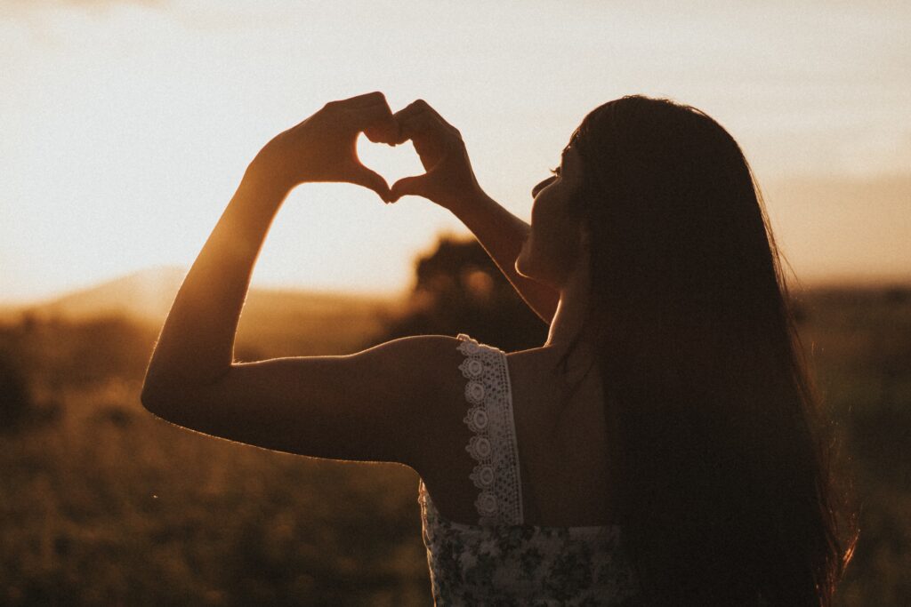A woman holds her hands out in a heart shape against the setting sun. Contact an empath therapist in Los Angeles, CA for support with empath therapy in Los Angeles, CA. Search for “empath therapist near me” to learn more.