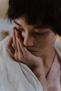A woman holds her face in her hand and looks sad. This could represent the grief one experiences and learns to cope with. 