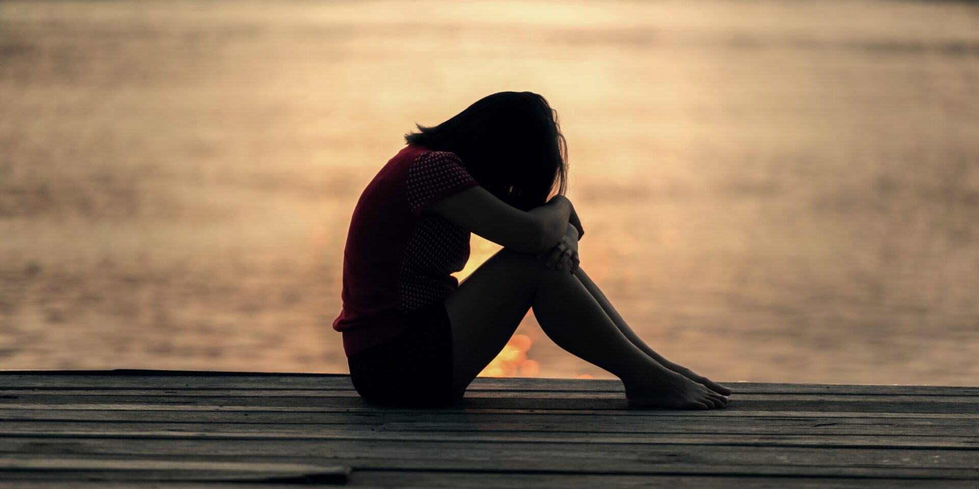 A woman sits with her head on her knees, crying. This could represent the grief for which one can learn practical ways to cope with in therapy.