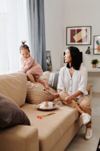 An Asian mother watches her child as they climb on the sofa. Learn how culturally sensitive therapy in Los Angeles, CA can offer support by searching for an Asian American therapist in Los Angeles today. 
