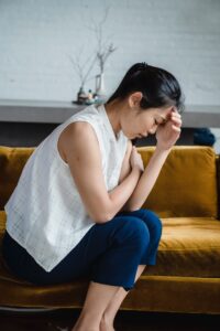 An upset woman sits with a hand near her head. Learn how an Asian American therapist in Los Angeles can offer support via Asian American therapy. Search for online therapy for Asian Americans to learn more today.
