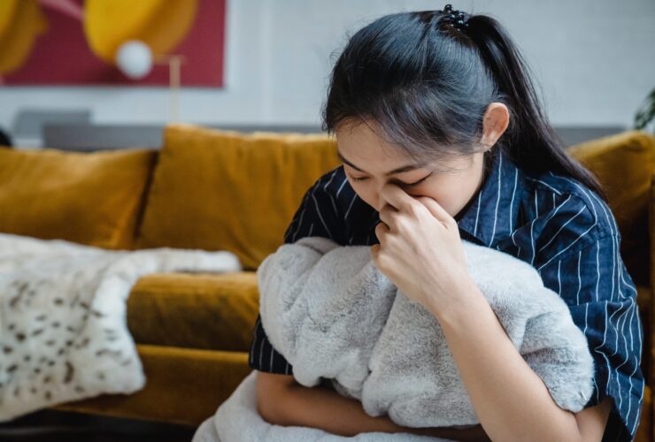 An asian american woman holds a pillow while wiping tears. Learn how a trauma therapist in Los Angeles, CA can offer therapy for ADHD in Los Angeles, CA and other services. Search for adult ADHD therapy and coaching to learn more.