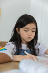 A young Asian girl stares at a piece of paper with a blank expression. This could represent the stress of trauma an Asian American therapist in Los Angeles can offer support with. Learn more about Asian American therapy in New York and other services by searching for trauma therapy in Los Angeles, CA today.
