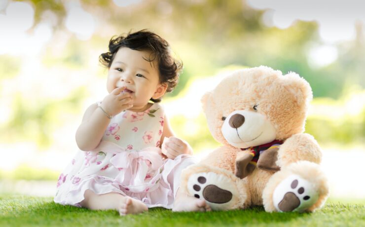 Asian baby next to a teddy bear. This can be representative of the asian american postpartum mom art support group.