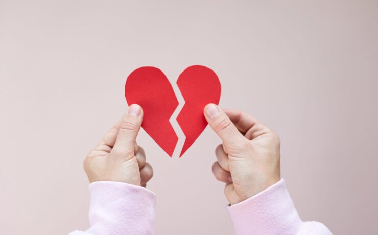 Two hands holding two sides of a paper heart broken in half. This could represent the heartbreak that individual therapy in LA and New York can address. Learn about trauma therapy near me and more today.
