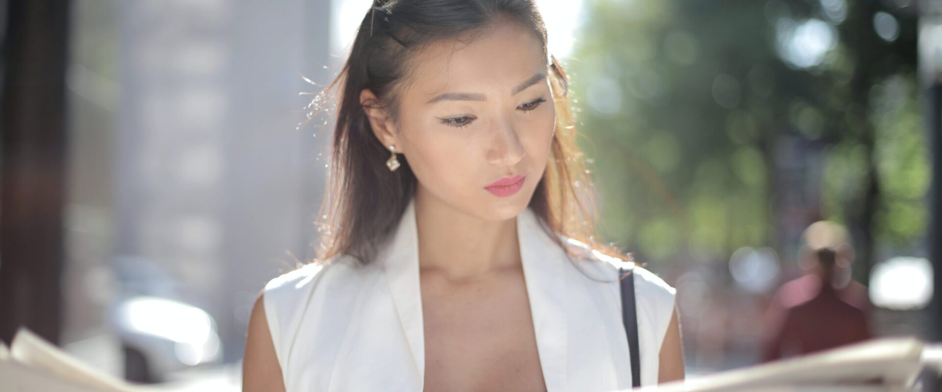A woman reads the newspaper on a sunny day. Search how Asian American therapy can offer support with addressing traumatic news. Contact an Asian American therapist in California for more support.