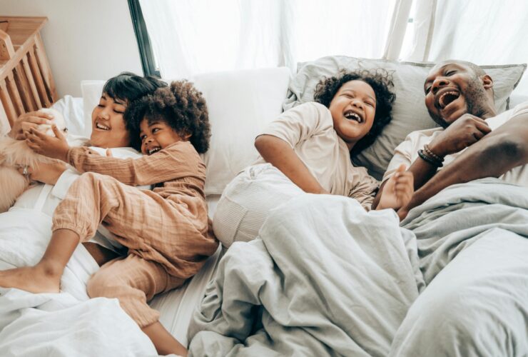 Two adults and two children laying on a bed. Learn how a neurodiversity-affirming therapist in Los Angeles, CA can offer therapy for couples and families in Los Angeles, CA and other services. Search for neurodiversity-affirming couples therapy or family therapy to learn more.