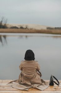 A woman sits alone on a wooden dock overlooking a lake. This could represent the isolation when dating that individual therapy in Los Angeles, CA can offer support in overcoming. Search for online couples therapy in California to learn more about culturally sensitive therapy in New York and other services.
