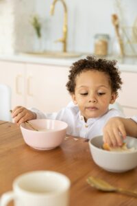 A child sitting at a dinner table reaches into a bowl while holding a cereal spoon in the other hand. This could represent the challenges of highly sensitive parents that therapy for highly sensitive people in Los Angeles, CA can address. Learn more about postpartum support in Los Angeles, CA and how it can offer support today.
