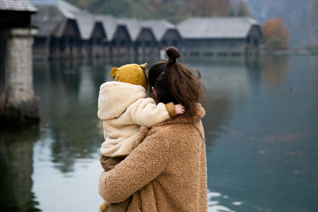A mother holds her child in her arms while looking out at an open lake. Learn more about highly sensitive person treatment in Los Angeles, CA, and how an online therapist in New York can offer support. Search for a stress management therapist in Los Angeles, CA to learn more.