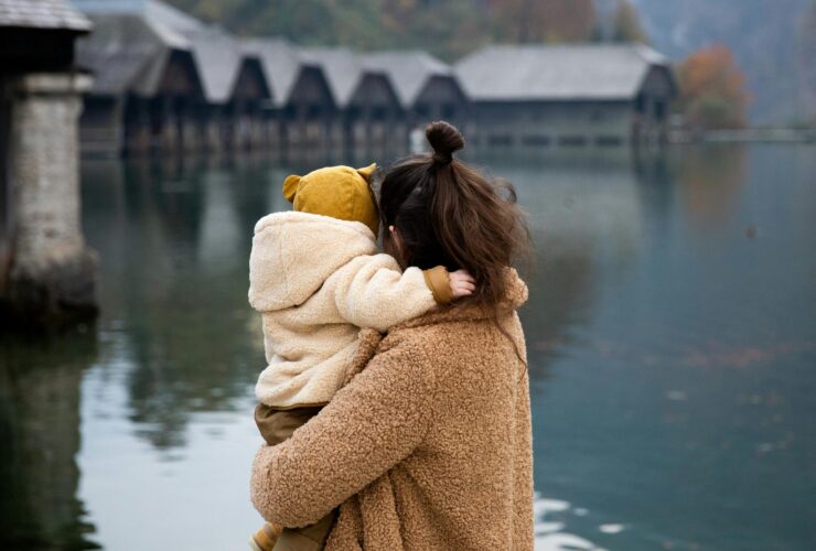 A woman holding a toddler, looking out onto a lake, with their backs to the viewer. Learn how a sensitivity-affirming therapist can help highly sensitive mom's today. Search online for sensitivity-affirming therapistst in Los Angeles and New York for more information.