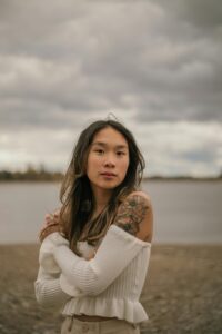 A woman hugs herself while smiling softly toward the camera. This could represent soothing techniques learned from an Asian American therapist in California. Search for individual therapy in Los Angeles, CA and other services like online anxiety treatment in California. 
