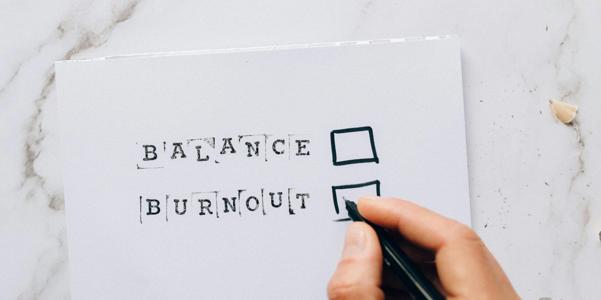 A close up of a hand holding a pen over a checkbox next to the word burnout. Learn how to find balance with a burnout therapist in Los Angeles, CA by searching for individual therapy in Los Angeles, CA. You can get in contact with an Asian American therapist near me today.