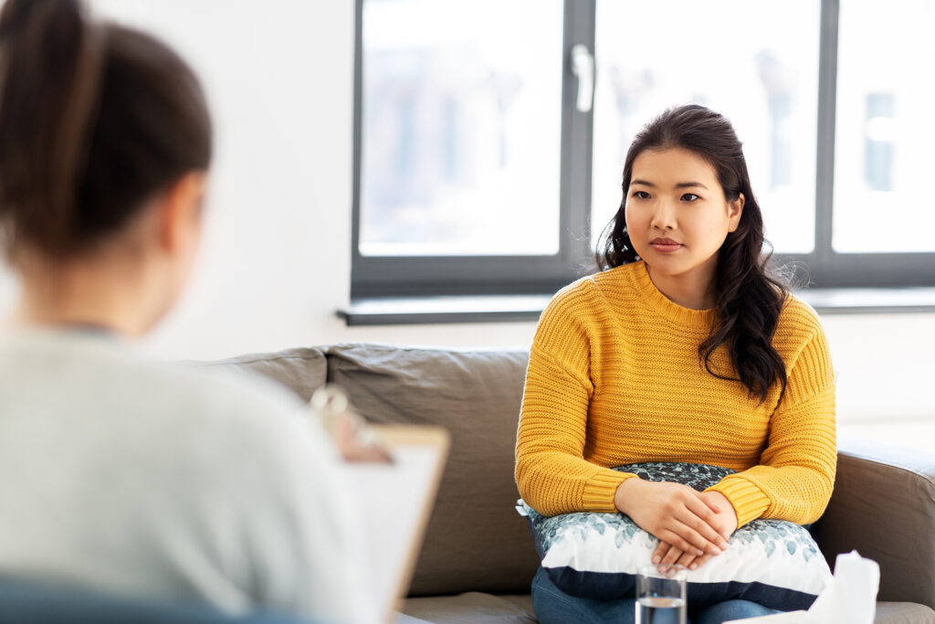 A woman holds a clipboard while sitting across from a woman listening intently. This could represent the cultural support an Asian American therapist in California can offer. Search for support in CA and NY and how culturally sensitive therapy in New York can help today.
