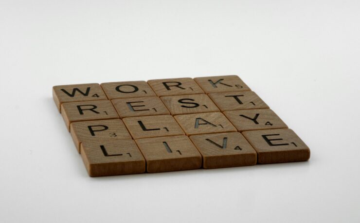 Four rows of wooden squares with printed letters that read, from top to bottom, "Work, Rest, Play, Live."