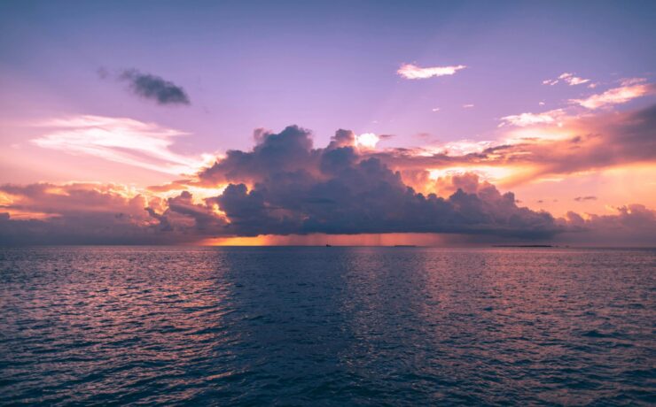 Clouds obscuring the sun during sunset over the ocean.