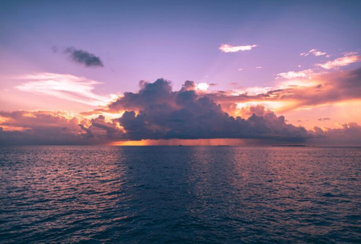 Clouds obscuring the sun during sunset over the ocean.