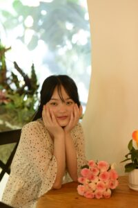 a woman sits at a table smiling happily with a bouquet of roses