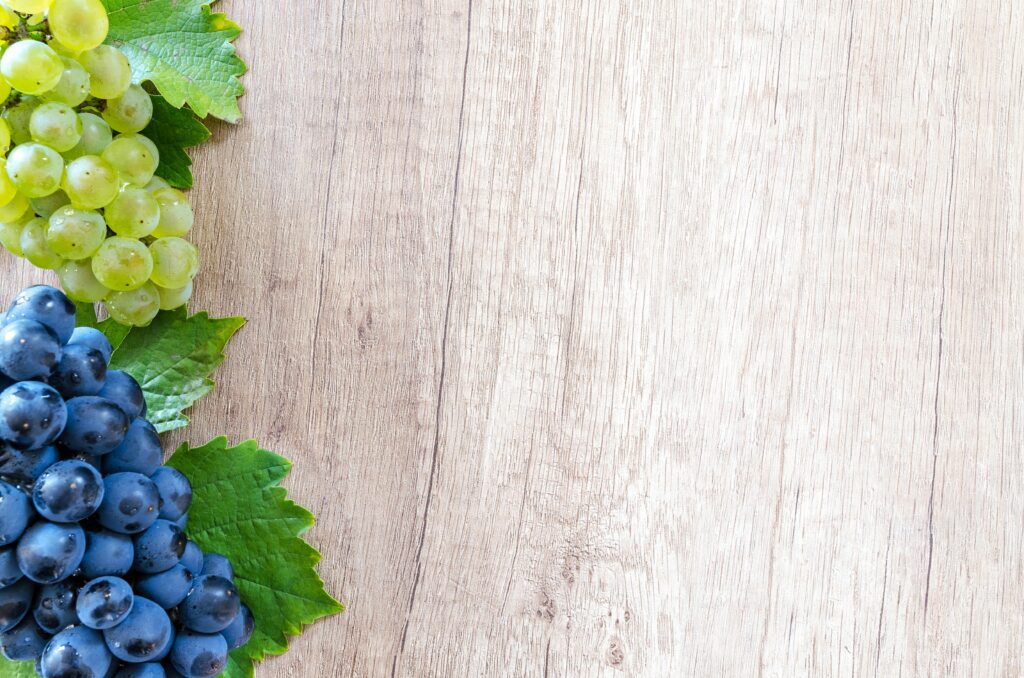 Shows a background of wood with green and blue grapes. Represents how an asian american therapist in los angeles can support you in individual therapy in los angeles, ca.