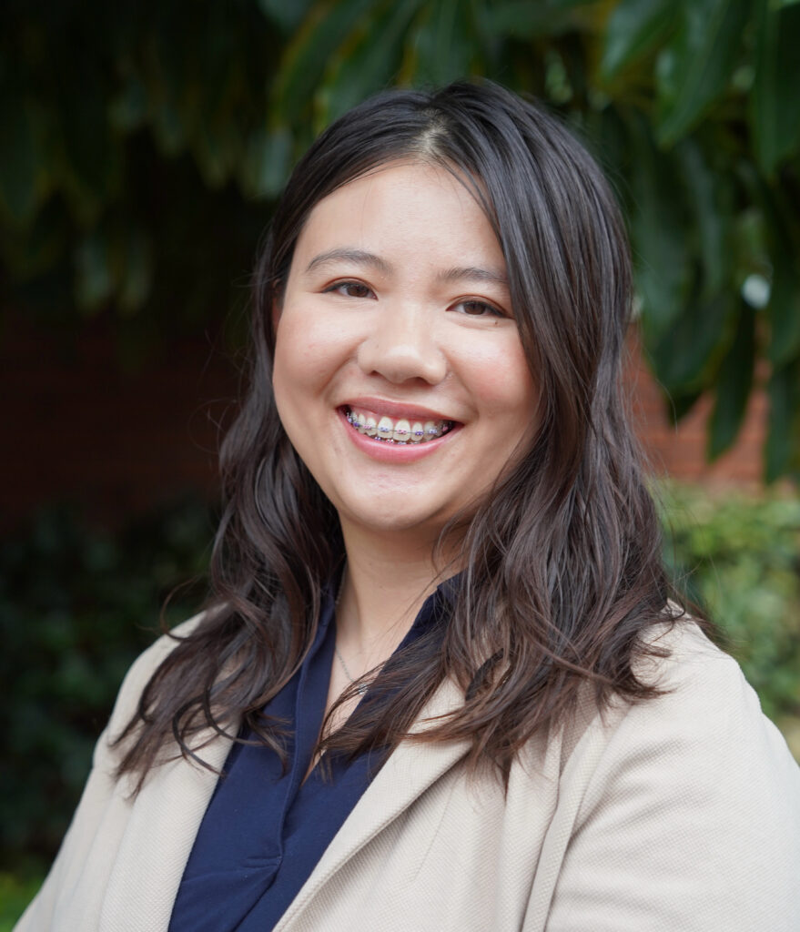 A Chinese-American therapist's headshot, smiling at the camera with the background of nature