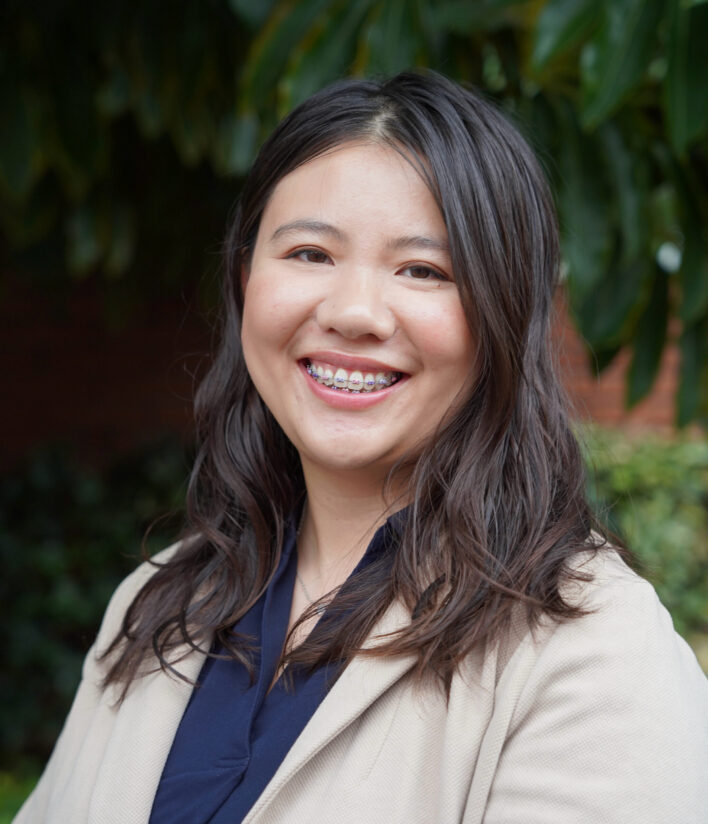 A Chinese-American therapist's headshot, smiling at the camera with the background of nature