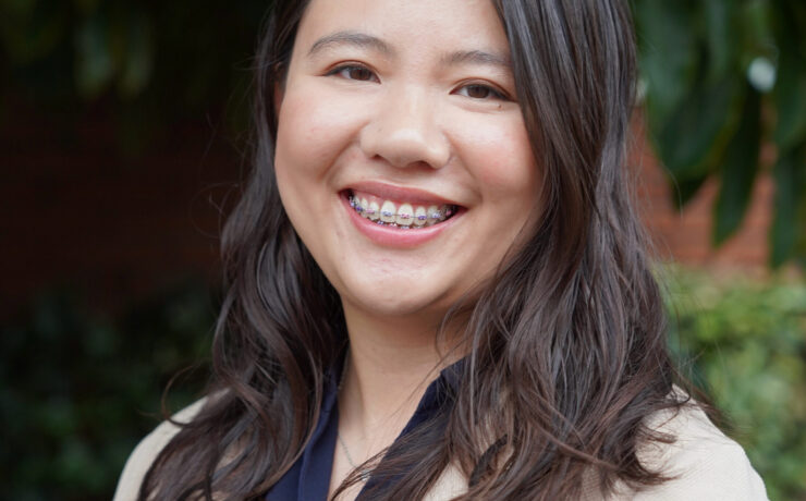 A Chinese-American therapist's headshot, smiling at the camera with the background of nature